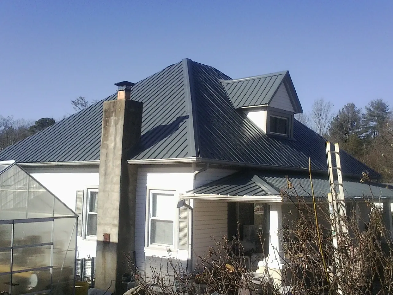 Dark blue standing seam metal roof on a white farmhouse with dormer — Slate & Tile Roof Repair by Roofing Brothers in West Bend