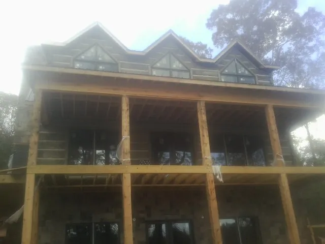 Dormers and porch framing on a large log home under construction — Roof Coating work by our crew in West Bend