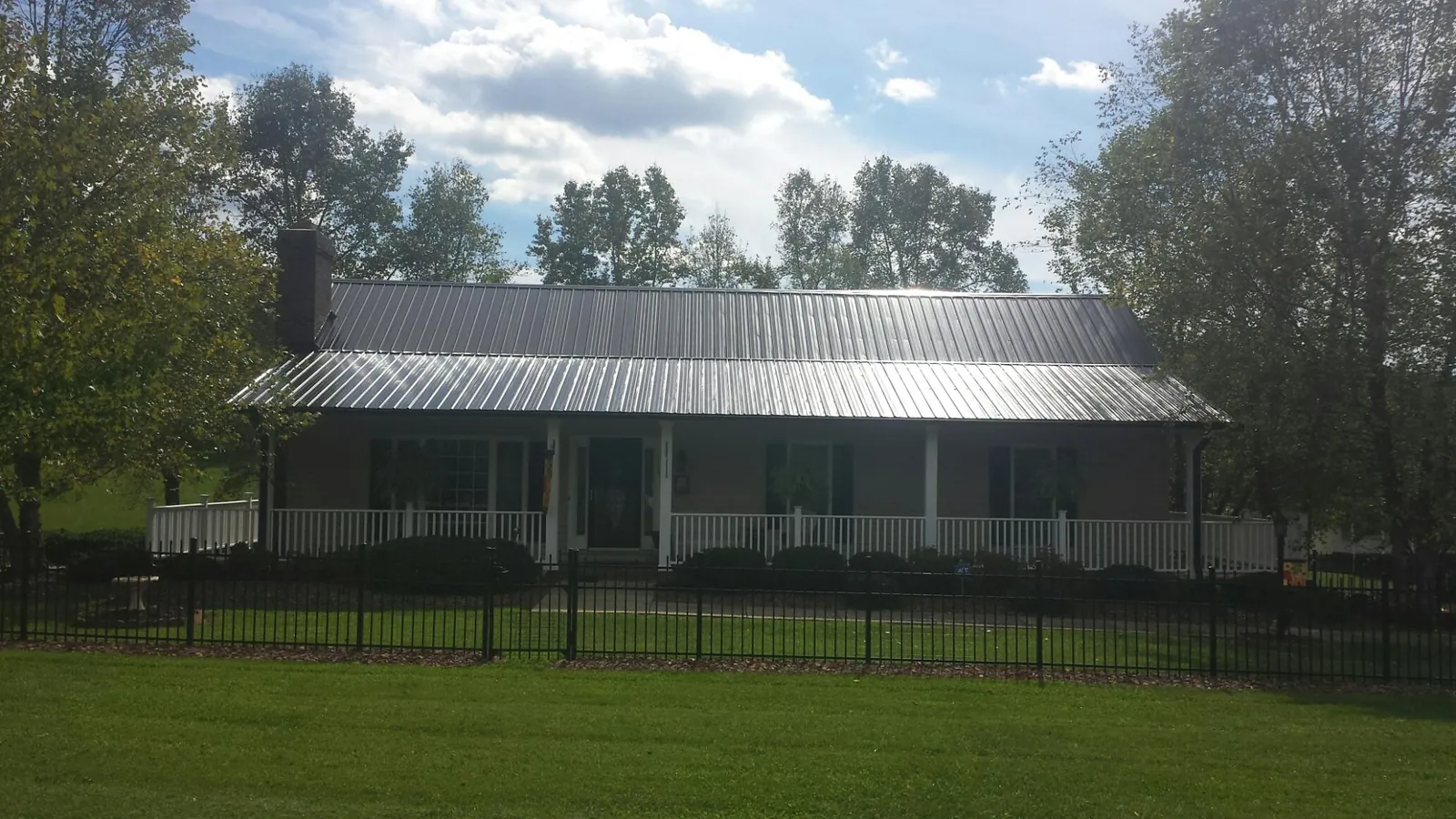Gray metal roof on a brick ranch with a full width front porch — Gutter Guard Installation work by our crew in West Bend