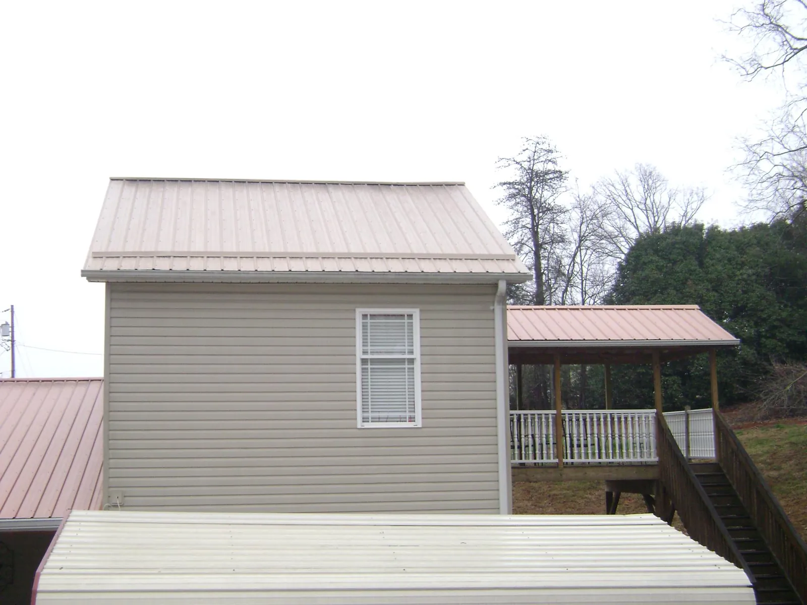 Tan metal roofs on a two story addition and attached porch, from a Roof Replacement job in West Bend