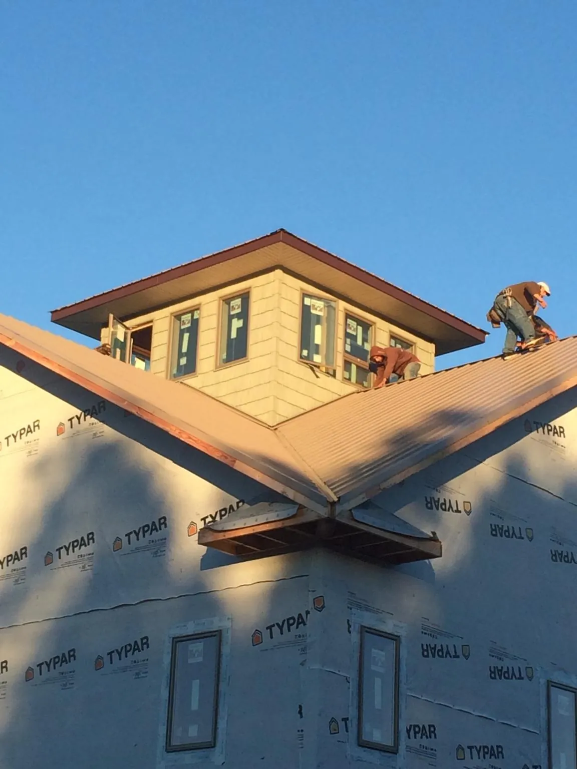 Roofers working around a rooftop cupola on a new metal roof at sunset — Roof Waterproofing in West Bend by Roofing Brothers